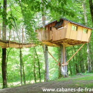 Cabane perchée dans les arbres, entourée de verdure en Bourgogne-Franche-Comté.