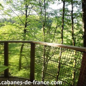 Cabane perchée en bois, offrant une vue imprenable sur la forêt verdoyante.