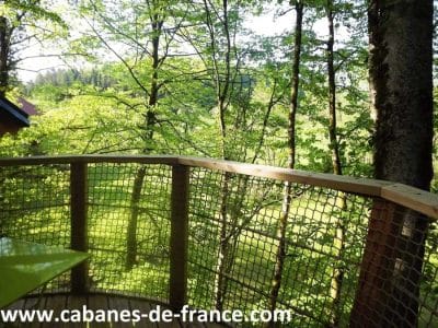Cabane perchée en bois, offrant une vue imprenable sur la forêt verdoyante.