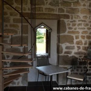 Cabane en pierre au Limousin, avec un escalier en bois et une vue sur la nature.