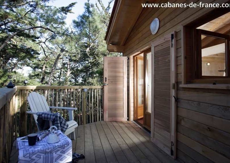 Cabane dans les arbres en Aquitaine, avec terrasse en bois et vue sur la forêt.