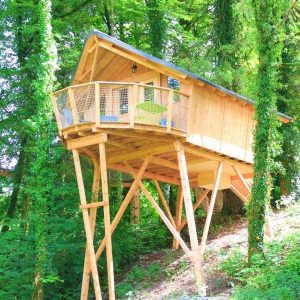 Cabane perchée en bois dans les arbres, entourée de verdure en Bourgogne-Franche-Comté.