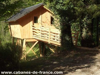 Cabane perchée en bois, entourée darbres verdoyants en Bourgogne-Franche-Comté.