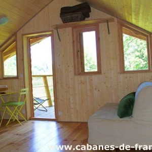 Cabane en bois lumineuse avec vue sur la nature, mobilier cosy et coloré.