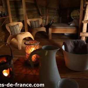 Cabane en bois à Ile-de-France, avec fauteuils en osier et lanternes chaleureuses.