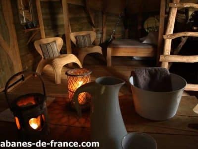 Cabane en bois à Ile-de-France, avec fauteuils en osier et lanternes chaleureuses.