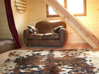 Cocon en bois en Aquitaine, avec un canapé confortable et un tapis en peau de vache.
