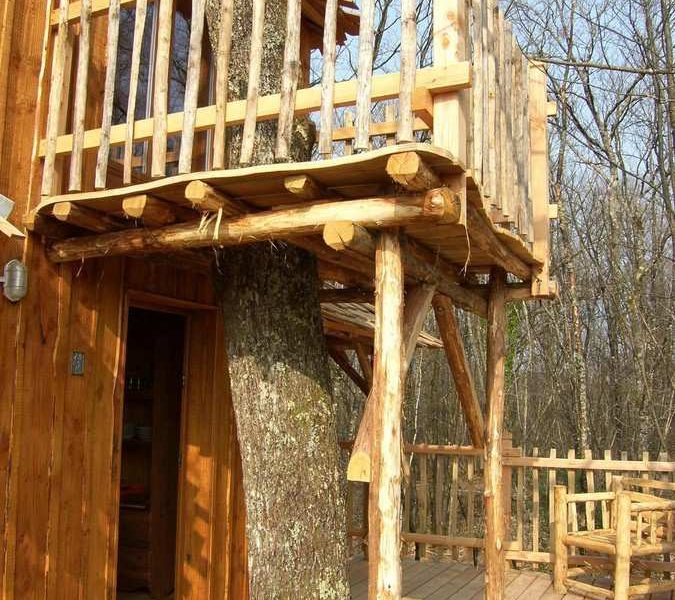 Cabane perchée dans un arbre en Aquitaine, avec un balcon en bois naturel.