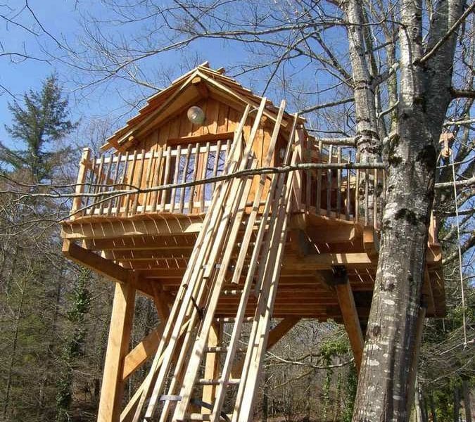 Cabane perchée dans les arbres en Aquitaine, avec une terrasse en bois accueillante.