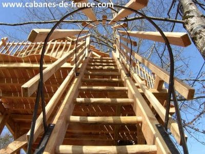 Cabane dans les arbres en Aquitaine, accès par un escalier en bois.