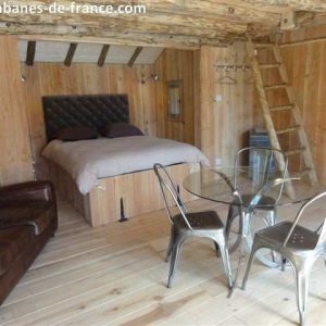 Cabane en bois en Aquitaine, avec lit double et coin repas en métal.