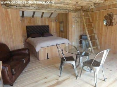 Cabane en bois en Aquitaine, avec lit double et coin repas en métal.
