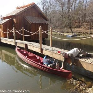 Cabane en bois sur pilotis au bord dun lac, avec un canoë rouge amarré.