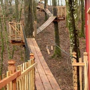Cabane perchée en Aquitaine, accessible par des passerelles en bois dans les arbres.