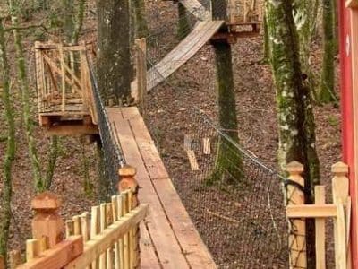 Cabane perchée en Aquitaine, accessible par des passerelles en bois dans les arbres.