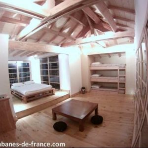 Hébergement insolite en Aquitaine : chambre spacieuse avec poutres apparentes et lits superposés.