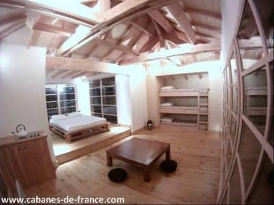 Hébergement insolite en Aquitaine : chambre spacieuse avec poutres apparentes et lits superposés.