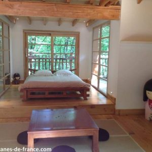 Cabane moderne en bois, lumineuse avec vue sur la nature, lit douillet.
