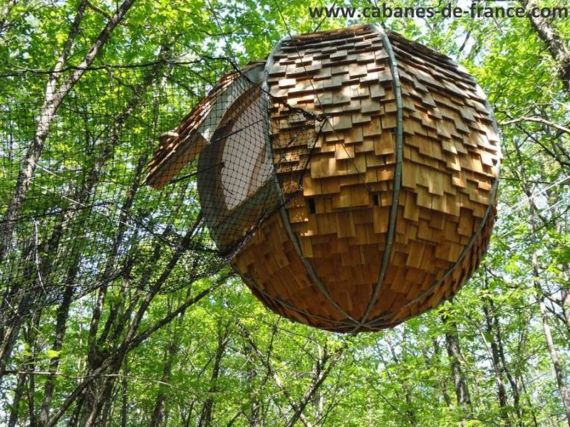 Cabane suspendue en bois, nichée dans les arbres en Aquitaine, offrant une vue unique.