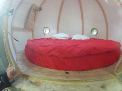 Hébergement insolite en Aquitaine : cabane ronde avec lit double et vue panoramique.