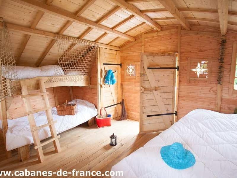 Cabane en bois à Ile-de-France, intérieur chaleureux avec lits superposés et déco nautique.