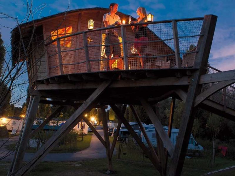 Cabane perchée en Île-de-France, avec un couple profitant dune soirée romantique.
