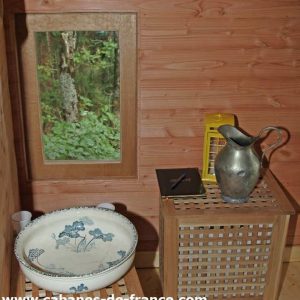Intérieur dune cabane en bois en Auvergne, avec un lavabo vintage et un miroir.