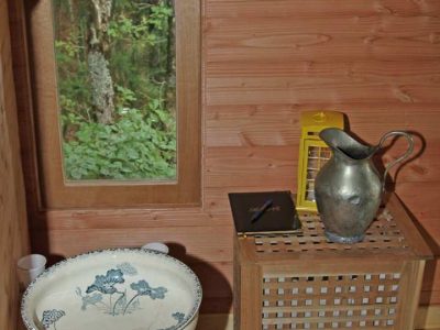 Intérieur dune cabane en bois en Auvergne, avec un lavabo vintage et un miroir.