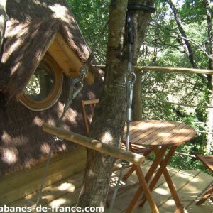 Cabane perchée en Bretagne, avec terrasse en bois et vue sur la nature environnante.