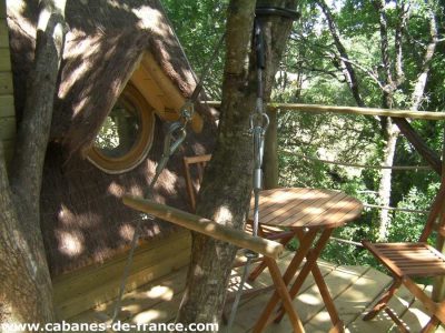 Cabane perchée en Bretagne, avec terrasse en bois et vue sur la nature environnante.