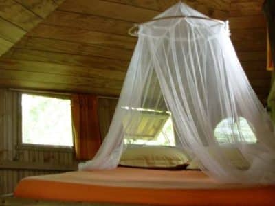 Cabane en bois en Bretagne avec un lit à baldaquin et une ambiance chaleureuse.
