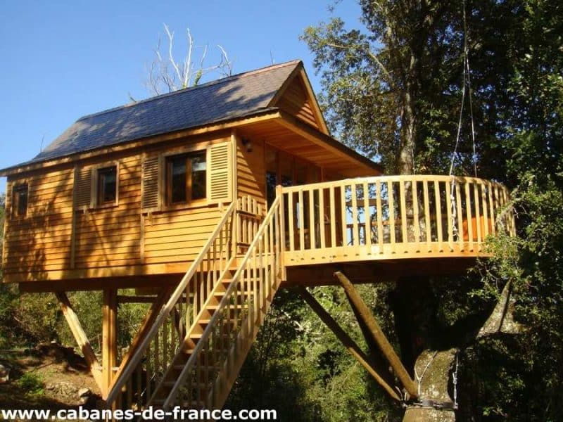 Cabane perchée en Corse, avec terrasse en bois et vue sur la nature environnante.