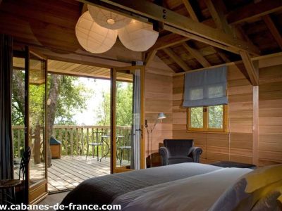Cabane en bois en Corse, avec un balcon et une vue sur la nature environnante.