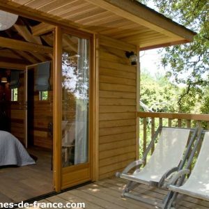 Cabane en bois en Corse, avec terrasse et chaises longues, vue sur la nature.