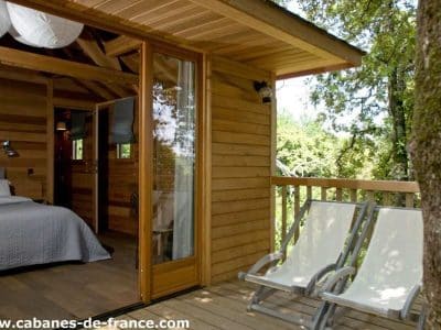 Cabane en bois en Corse, avec terrasse et chaises longues, vue sur la nature.