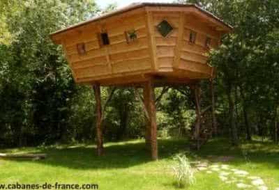 Cabane perchée en bois dans les arbres, entourée de verdure en Bretagne.