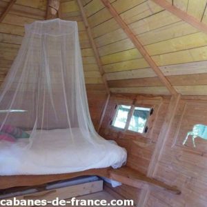 Cabane en bois avec lit douillet, décorée de motifs animaliers sur les murs.