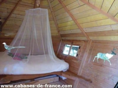 Cabane en bois avec lit douillet, décorée de motifs animaliers sur les murs.