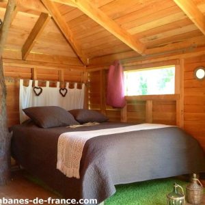 Cabane en bois cosy avec lit douillet et décoration chaleureuse en Provence-Alpes-Côte dAzur.