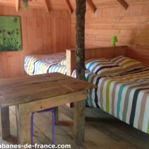 Cabane en bois avec lits à rayures et table rustique, au cœur de la Provence.