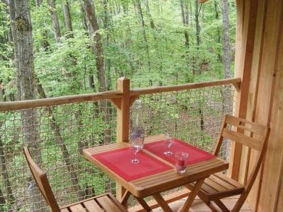 Cabane perchée en bois en Auvergne-Rhône-Alpes, avec vue sur la forêt verdoyante.