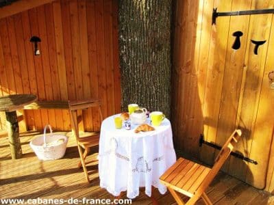 Cabane en bois à Champagne-Ardennes, avec une table dressée sous un arbre.