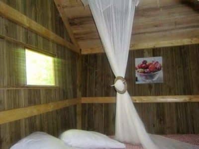 Cabane en bois à Champagne-Ardennes, lit douillet avec voilage élégant.