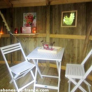 Cabane en bois à Champagne-Ardennes, avec table et chaises blanches élégantes.