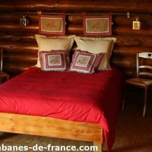 Cabane en bois en Bourgogne, lit douillet avec coussins à motifs.