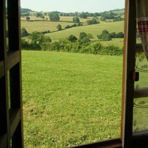Vue depuis une cabane en bois en Bourgogne, sur un paysage verdoyant et vallonné.