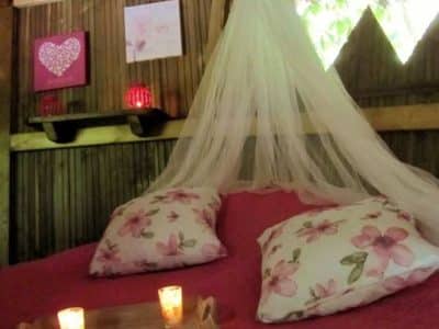 Cabane romantique en Champagne-Ardenne, lit douillet avec coussins fleuris et bougies.