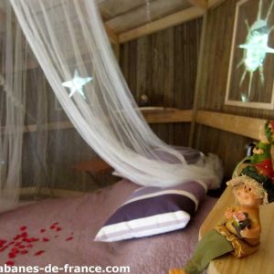 Cabanes perchées en Champagne-Ardenne, décor champêtre avec voilage et figurines.