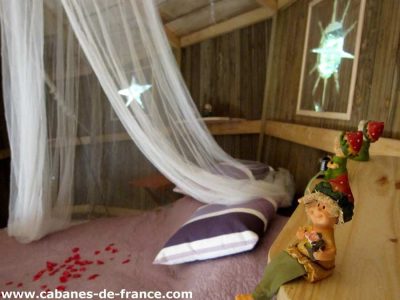 Cabanes perchées en Champagne-Ardenne, décor champêtre avec voilage et figurines.