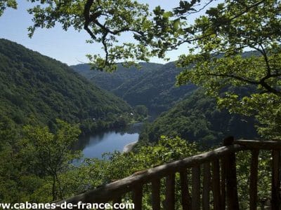 Cabane perchée dans les arbres, vue panoramique sur la vallée verdoyante.